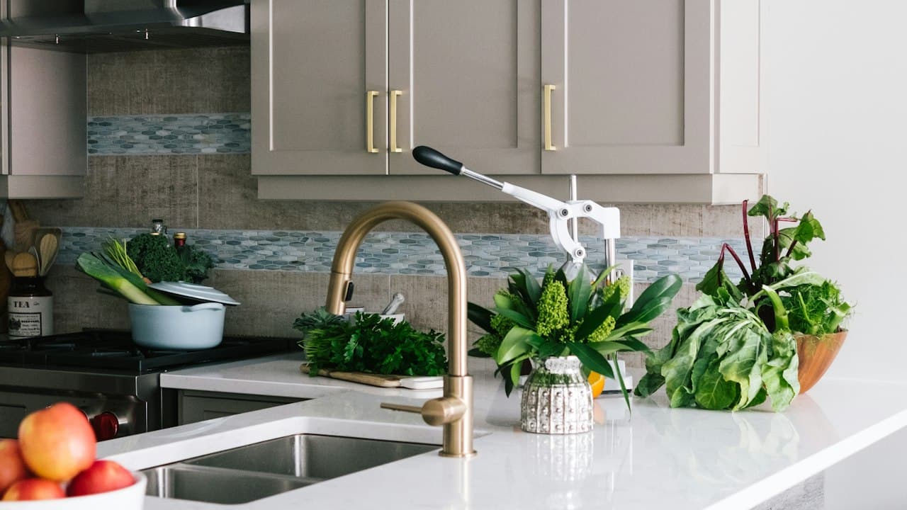 Kitchen backsplash in a Vancouver, WA home with wood-look tile, a glass mosaic accent band, quartz countertop and brass faucet after a Clark County kitchen remodel